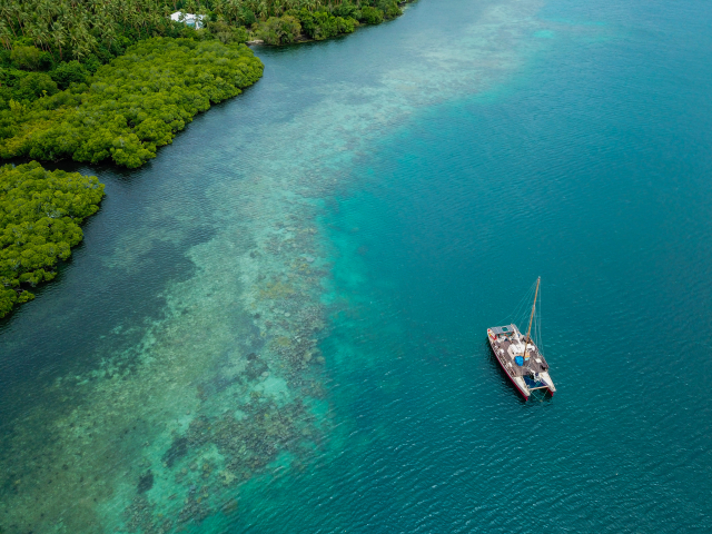 A catamaran (Vaka Motu) of the Okeanos Foundation off the reef fringe of Maskelyne Island (Photo: Christopher Malili, Okeanos Foundation for the Sea)