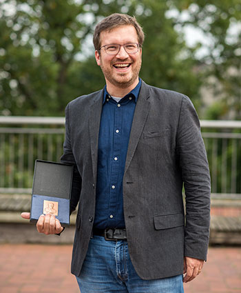 ZMT geoscientist Nils Moosdorf honoured with Hermann Credner Prize  During its GeoBremen 2017 conference at the University of Bremen the „Deutsche Geologische Gesellschaft – Geologische Vereinigung (DGGV)“ awarded the Hermann Credner Prize to Dr. Nils Moosdorf from the Leibniz Centre for Tropical Marine Research (ZMT). The 37-year-old has received the accolade in recognition of his research in the field of submarine groundwater discharge and global biogeochemical cycles. Now endowed with 5000 Euro, the Hermann Credner Prize for young scientists (under the age of 40) has been awarded annually since 1960. „The DGGV honours an exceptional and innovative young scientist, who has already gained an international reputation in his filed,” said Professor Jan Behrmann, President of the DGGV at the awards ceremony. Since his dissertation Nils Moosdorf has studied the role of rocks in the global cycling of carbon, silicon or phosphor. Furthermore, Moosdorf investigated whether artificially accelerated rock weathering could contribute to reducing the CO2 concentration in the atmosphere. Due to his findings geo sciences is now better equipped to better understand today‘s biogeochemical cycles and to understand their past and future changes. As head of a junior research group at ZMT Nils Moosdorf currently studies the role of direct groundwater discharge into the ocean in local and global land-ocean solute fluxes. For his research he not only relies on his own field studies in South East Asia or Tahiti but also uses large data sets from publicised studies, in order to find new aspects within the data.  Local knowledge about fresh water discharge are also an important source of information for him. In her laudation, Professor Hildegard Westphal, Scientific Director of ZMT, described Moosdorf as a „scientist who crosses borders and who connects the studies of land and water across disciplinary boundaries“. „Nutrient transport with groundwater not only influences marine ecosystems but can also have potential effects on the maritime economy“, said Westphal. „Yet, invisible connection underground is seldom studied in detail. Not many researchers are looking at the land and are thinking of the sea.“ In his work group Moosdorf unites geologists and hydrologists as well as biologists and mineralogists and sees the chance for new findings in crossing disciplinary boundaries. „He is a representative of a new generation of scientists who want to comprehend our changing world in its wider dynamic ¬– an understanding of science that the DGGV honours today with the Hermann Credner Prize,“ Westphal continued. For Nils Moosdorf the award is an important acknowledgement in his young scientific career. „I am very happy about this honour and would not only like to thank the DGGV but also in particular those colleagues who taught me so much in lively discussions. Scientific exchange has always been and will continue to be exciting and inspiring for me.”