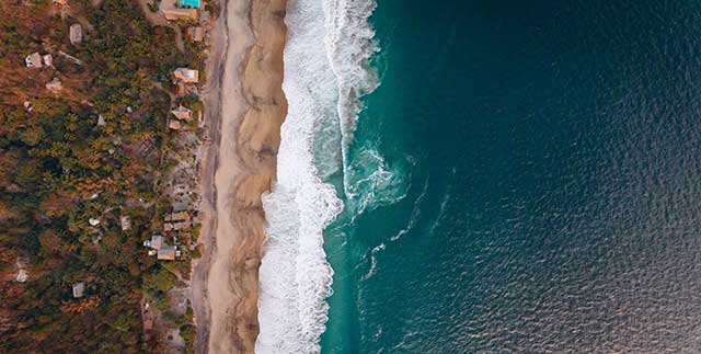 Luftaufnahme einer Küste mit Wellen, die auf das Land treffen