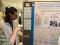 Zwei Konferenzteilnehmende diskutieren vor einem wissenschaftlichen Poster &uuml;ber Blue Justice in Bangladesch und zeigen dabei auf Grafiken und Diagramme.