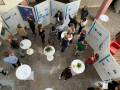 A group of people are gathered in a bright indoor atrium for a professional event or conference.
