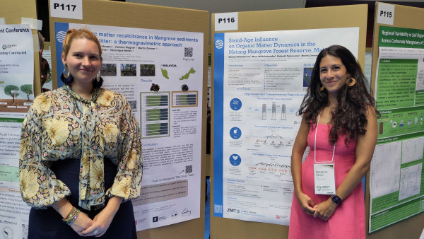 Zwei Konferenzteilnehmerinnen stehen vor wissenschaftlichen Posterpräsentationen während einer Fachkonferenz zu Mangrovenforschung. 