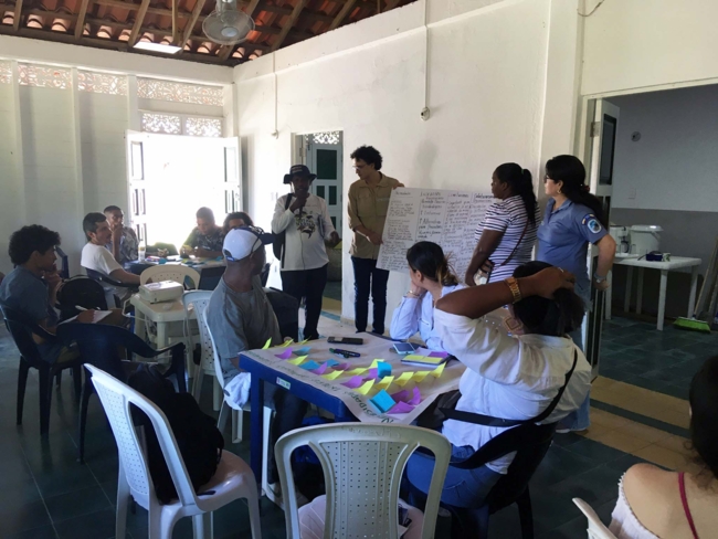 The photo shsow a group of people in a workshop in front of a screen