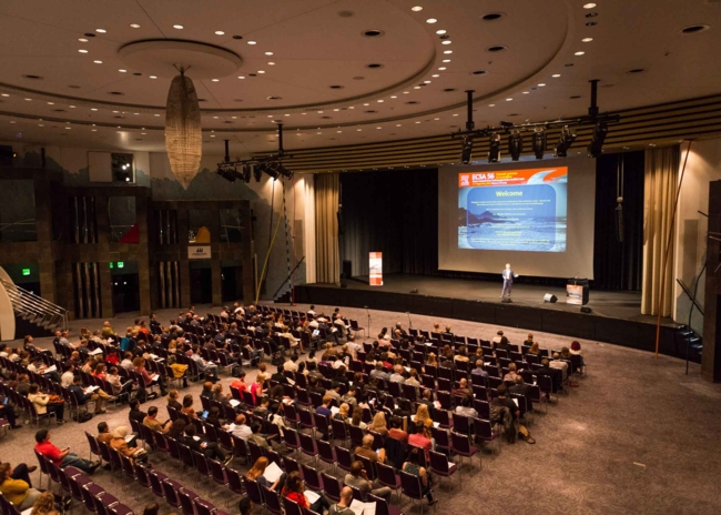Blick von oben auf ein Publikum in einem großen Konfernzsaalgr