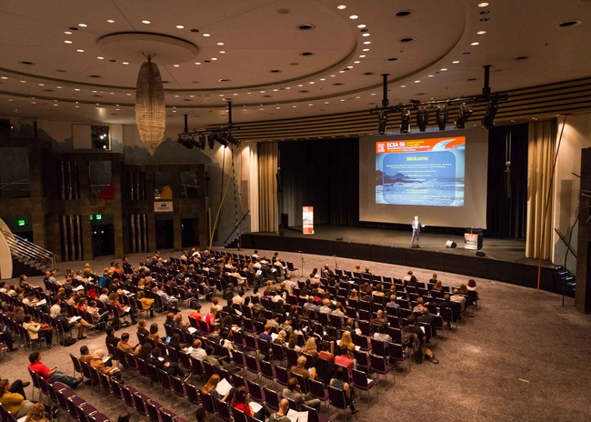 Blick von oben auf ein Publikum in einem großen Konfernzsaalgr