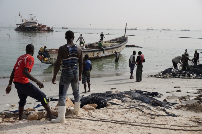 Senegalesische Fischer, im Hintergrund pumpen Trawler ihren Fang in die Fischmehlfabrik in Nouadhibou, Mauretanien | Foto: Henryk Alff