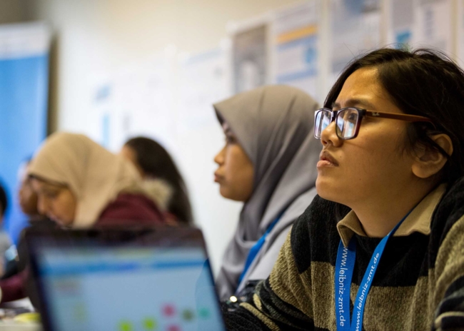 Side view of a woman with glasses listening spellbound to a lecture